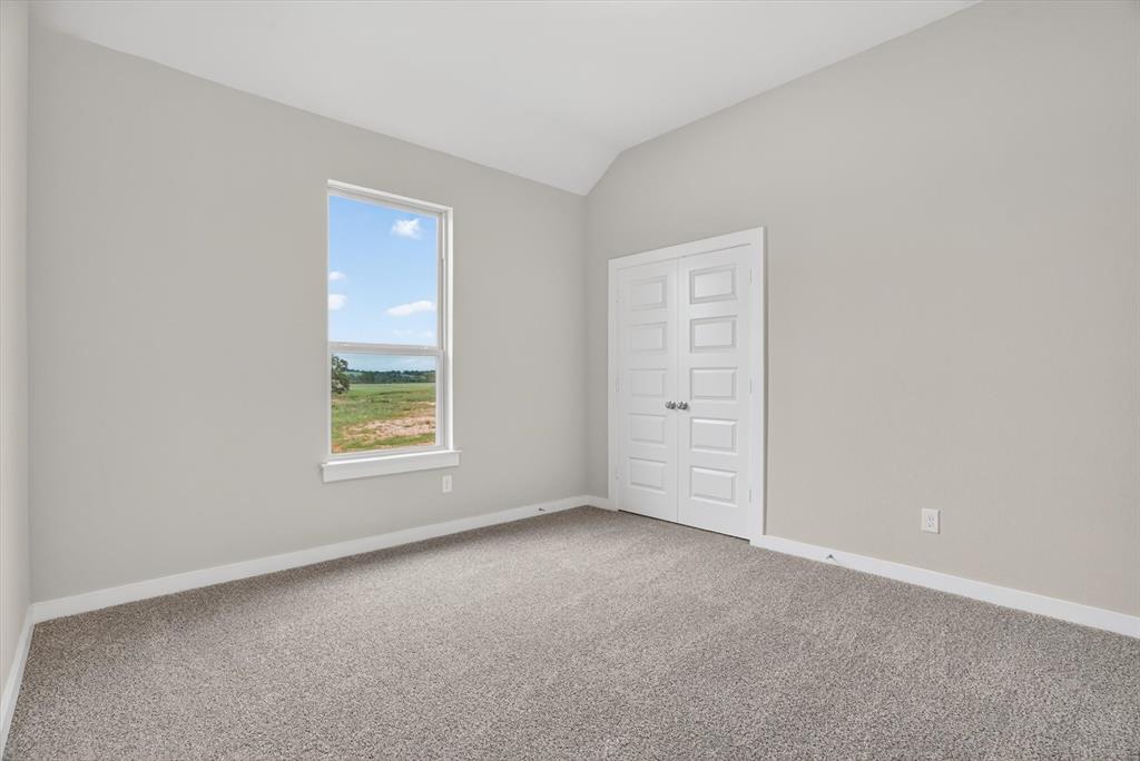 504 Clifton Court Springtown, TX 76082 - Photo 24 of 36 Neutral-toned wall paint and vaulted ceiling with carpet flooring