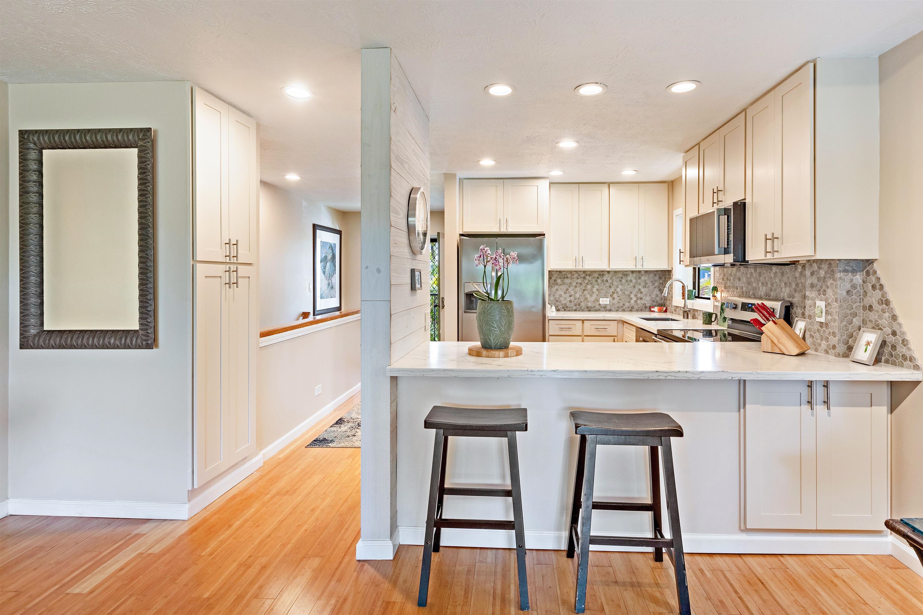 3788 Lower Honoapiilani Road, Unit D101 Lahaina, HI 96761 - Photo 9 of 40 a kitchen with stainless steel appliances granite countertop a stove a sink a refrigerator and white cabinets with wooden floor