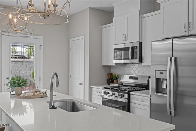 a kitchen with stainless steel appliances granite countertop a sink a stove refrigerator and microwave with wooden floor