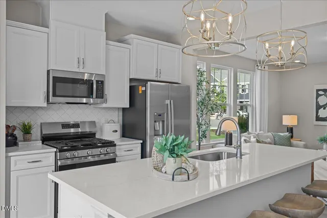 a kitchen with stainless steel appliances granite countertop a refrigerator a stove a sink dishwasher a dining table and chairs with wooden floor