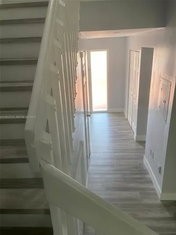 a view of a hallway with wooden floor and staircase