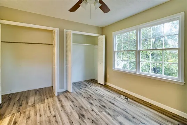 a view of empty room with wooden floor and fan