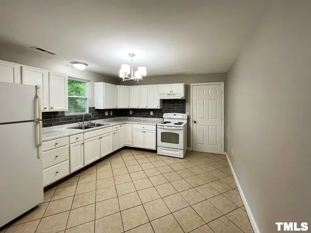 a kitchen with white cabinets a sink appliances and a window
