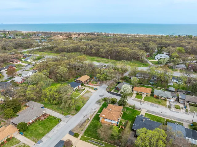 an aerial view of ocean and residential houses with outdoor space