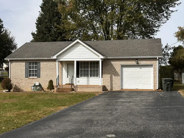 a front view of a house with a garden and trees