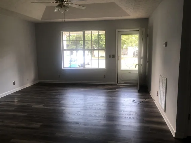 an empty room with wooden floor and windows