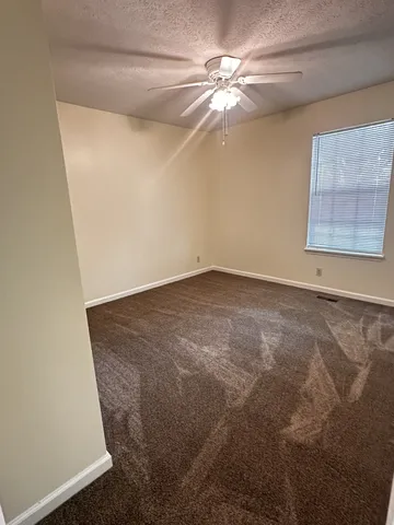 en empty room with windows and ceiling fan