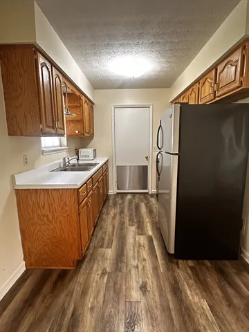 a kitchen with sink a refrigerator and wooden floor