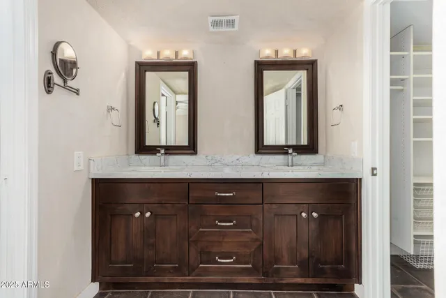 a bathroom with mirror two sinks and a toilet