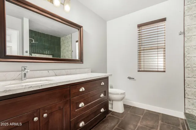 a bathroom with a granite countertop sink a toilet and a mirror