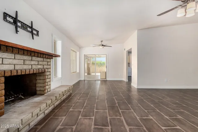 a view of an empty room with wooden floor fireplace and a window
