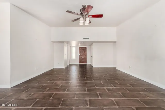 a view of an empty room with window and a kitchen