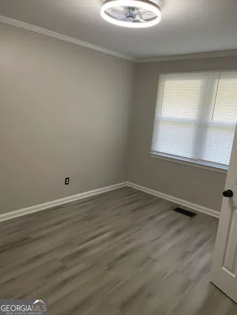 a view of an empty room with wooden floor and a window
