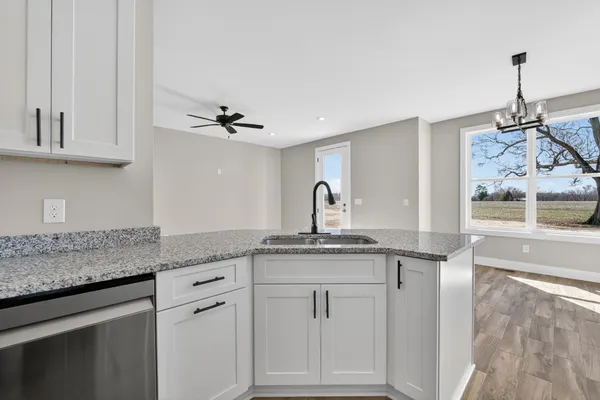 a kitchen with stainless steel appliances granite countertop a stove a sink and white cabinets