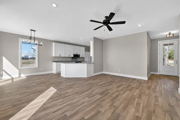 a view of empty room with wooden floor and ceiling fan