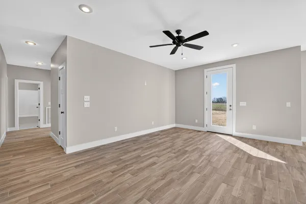 a view of empty room with wooden floor and fan