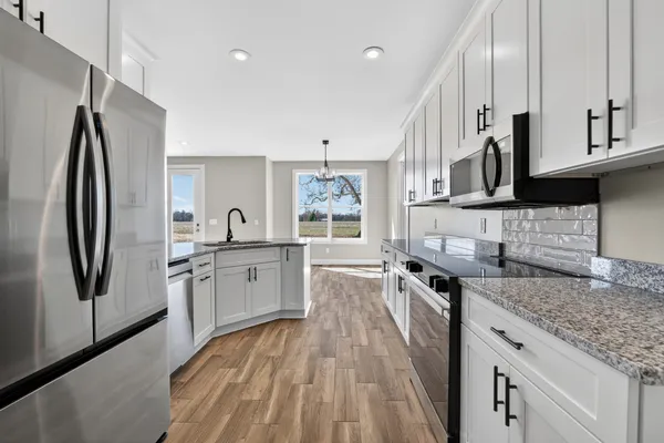 a large kitchen with stainless steel appliances granite countertop a lot of counter space and wooden floors