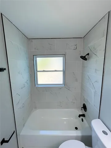 a bathroom with a bathtub a window and a shower