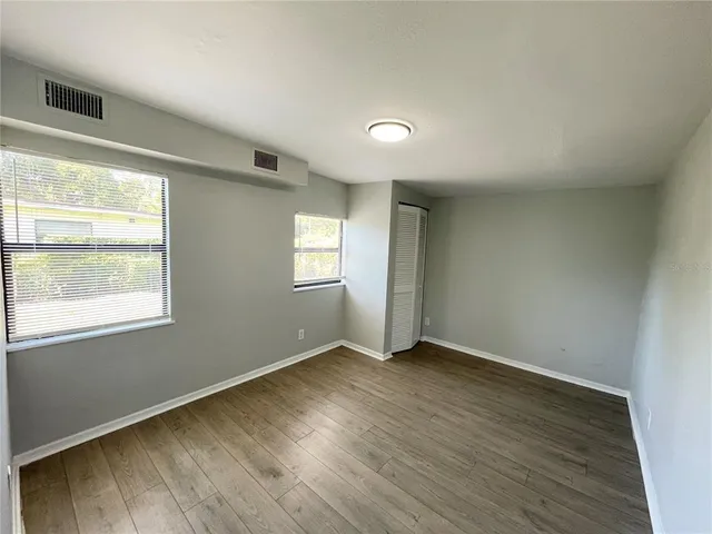 an empty room with wooden floor and windows