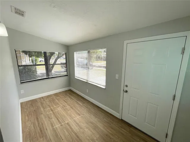 an empty room with wooden floor and windows