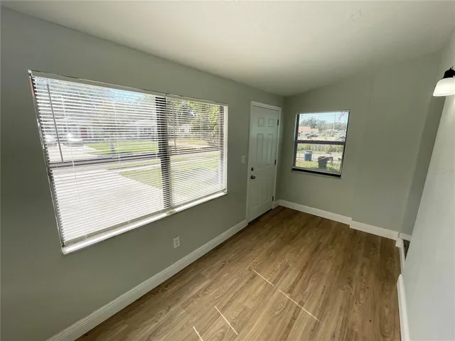 a view of an empty room with wooden floor and a window