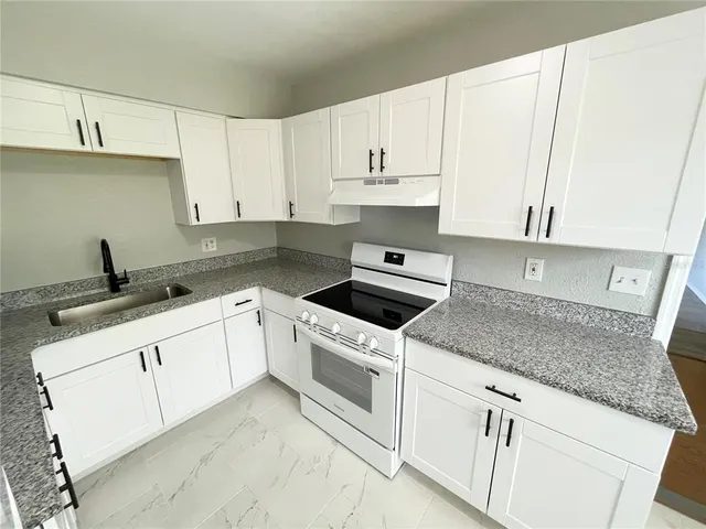 a kitchen with granite countertop white cabinets and white appliances