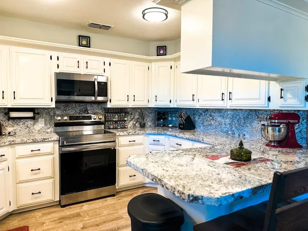 a kitchen with stainless steel appliances granite countertop a stove and a microwave