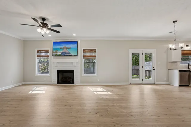 a view of a livingroom with wooden floor a ceiling fan and window