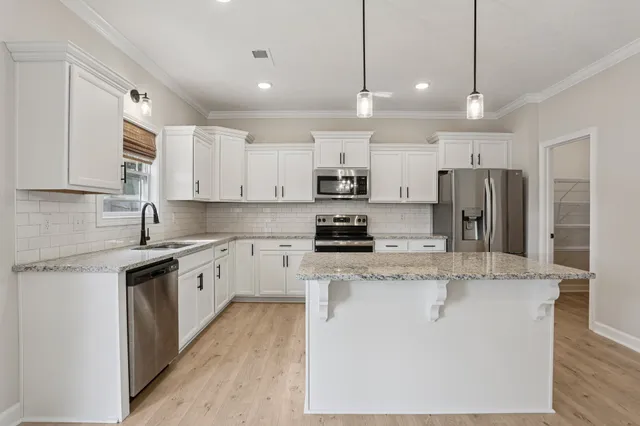 a kitchen with kitchen island granite countertop a stove a sink a center island a dining table and chairs