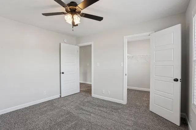 an empty room with windows and fan