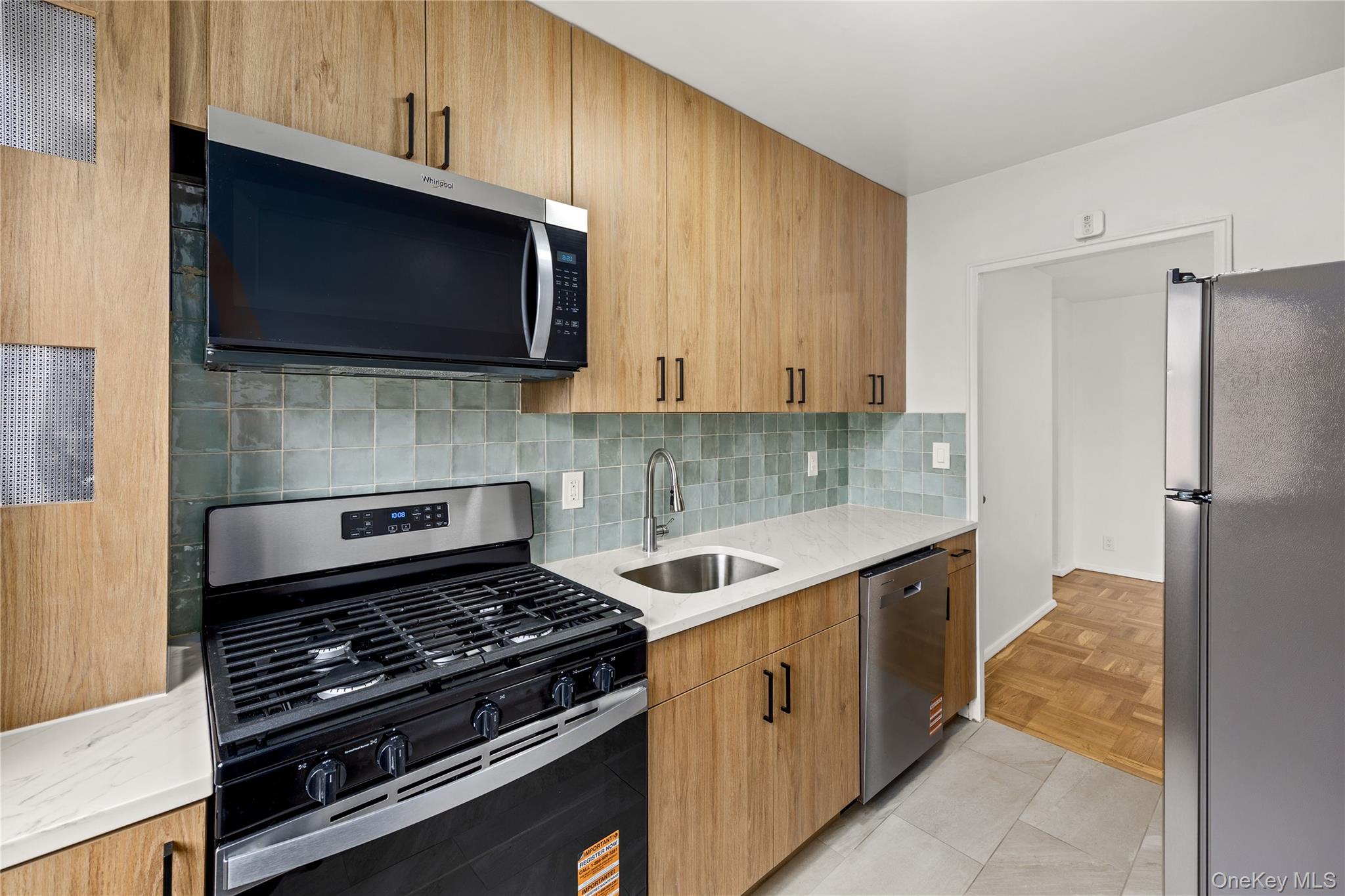 21-66 33rd Road, Unit 12B Queens, NY 11106 - Photo 13 of 23 a kitchen with stainless steel appliances a sink a stove a microwave and cabinets