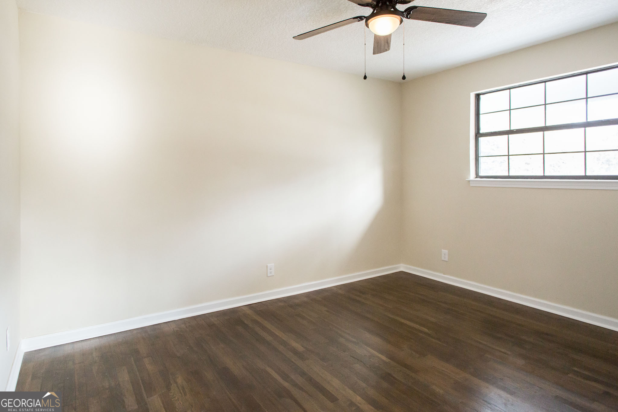 407 Pineview Drive Waycross, GA 31501 - Photo 19 of 35 an empty room with wooden floor chandelier fan and windows
