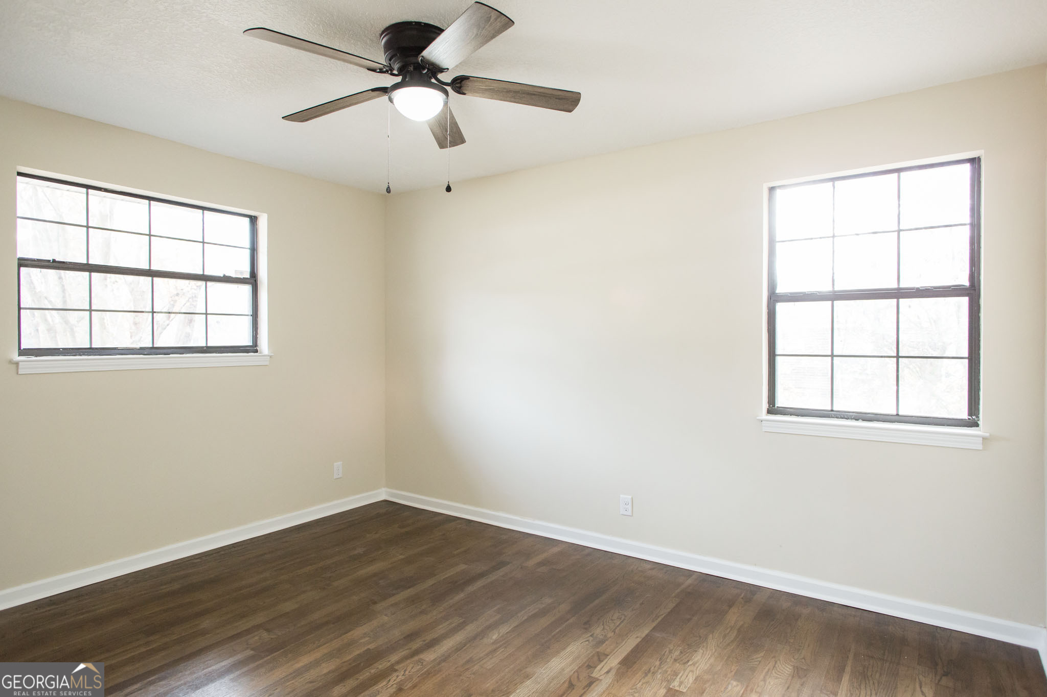 407 Pineview Drive Waycross, GA 31501 - Photo 21 of 35 an empty room with wooden floor ceiling fan and windows