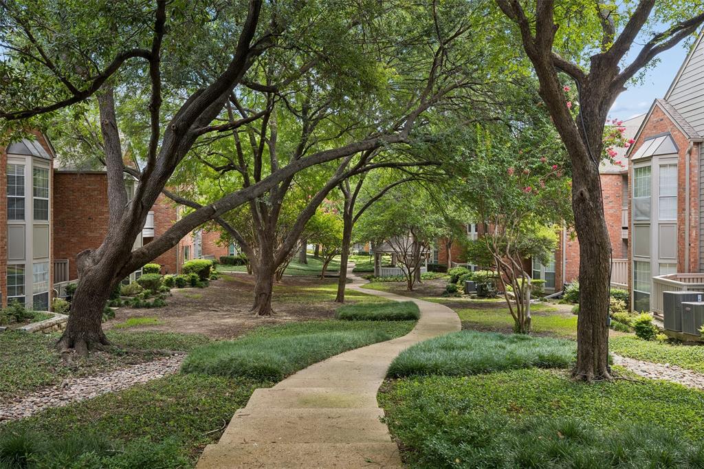 12660 Hillcrest Road, Unit 7205 Dallas, TX 75230 - Photo 22 of 25 Landscaped communal courtyard featuring a winding concrete pathway, mature trees, and low-lying ground cover