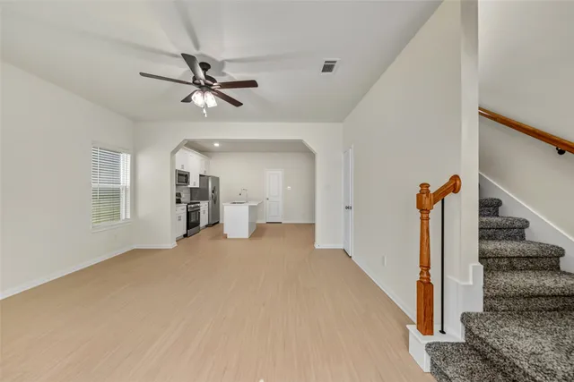 a view of a livingroom with wooden floor and ceiling fan