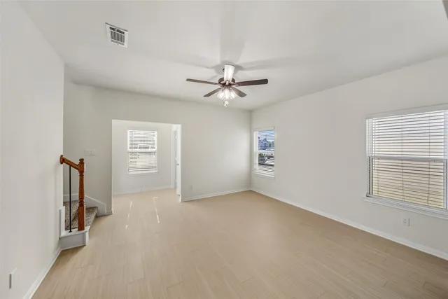 an empty room with windows and fan