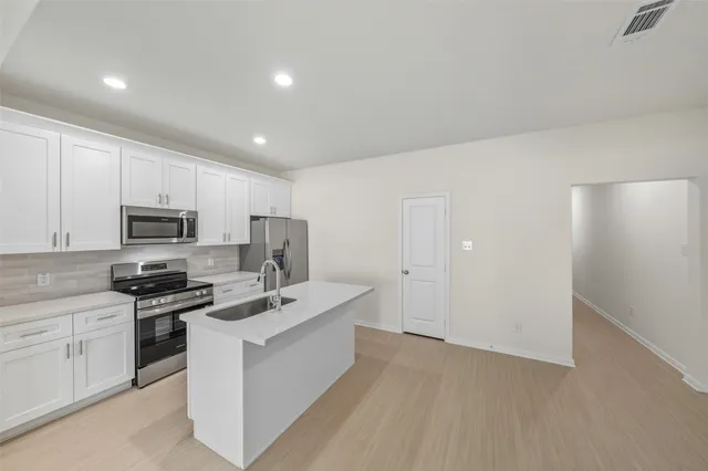 a kitchen with white cabinets stainless steel appliances and a counter space