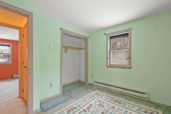 a view of an empty room with closet and a window