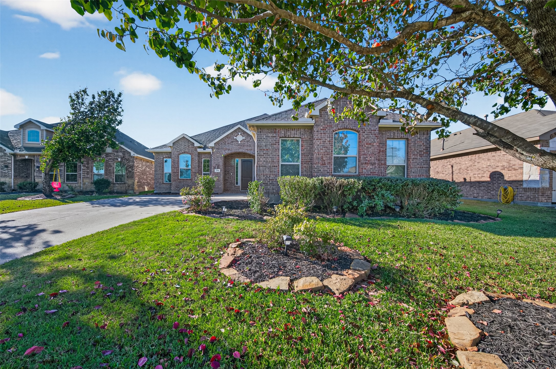 a front view of a house with a yard and large tree