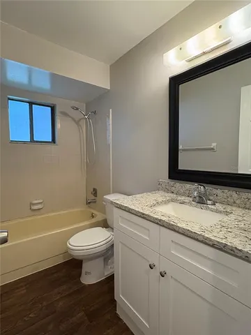 a bathroom with a granite countertop sink a toilet and a bathtub