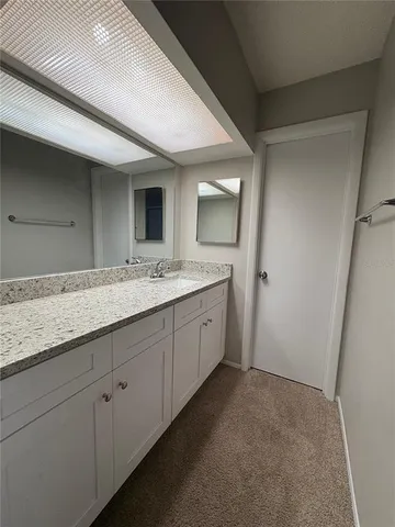 a spacious bathroom with a granite countertop sink and a mirror
