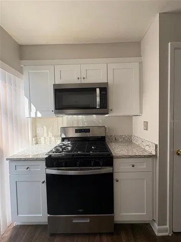 a kitchen with granite countertop white cabinets sink and stainless steel appliances