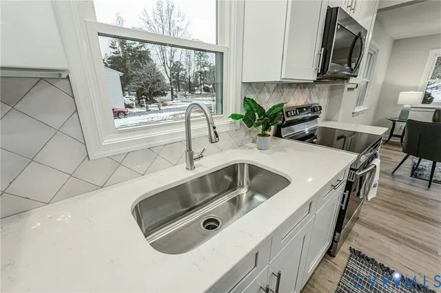 a kitchen with stainless steel appliances a sink a stove a microwave a sink and cabinets