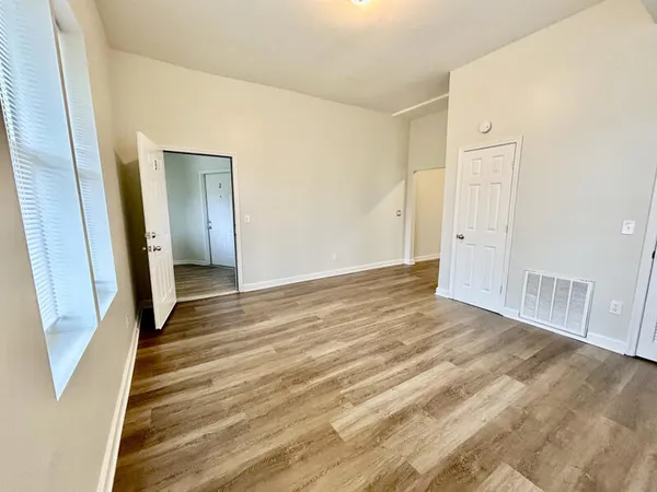 a view of an empty room with wooden floor and a bathroom