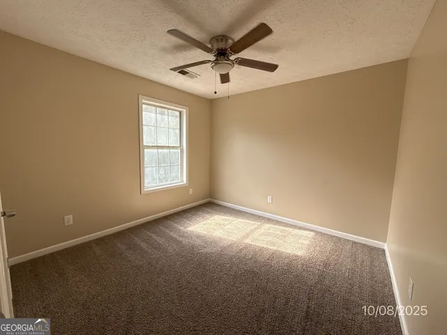an empty room with windows and ceiling fan