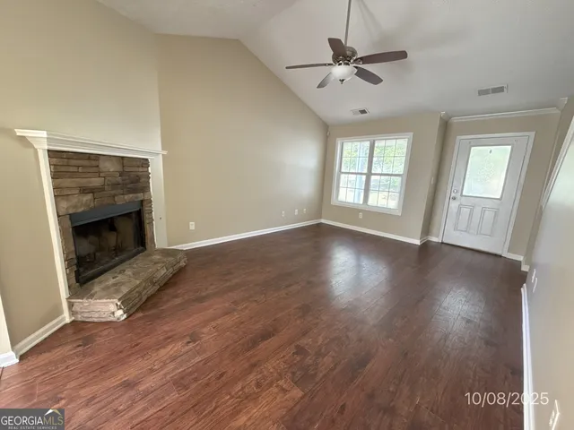 an empty room with wooden floor a ceiling fan and a fireplace