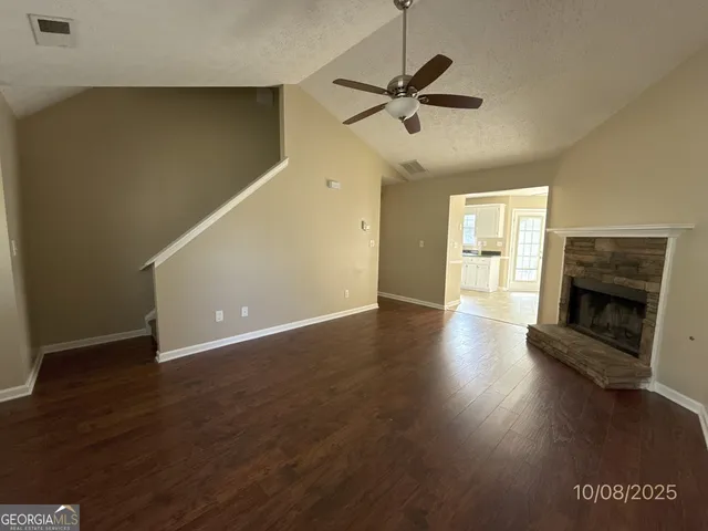 an empty room with wooden floor fireplace and windows