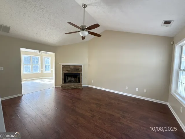 an empty room with wooden floor a ceiling fan and windows