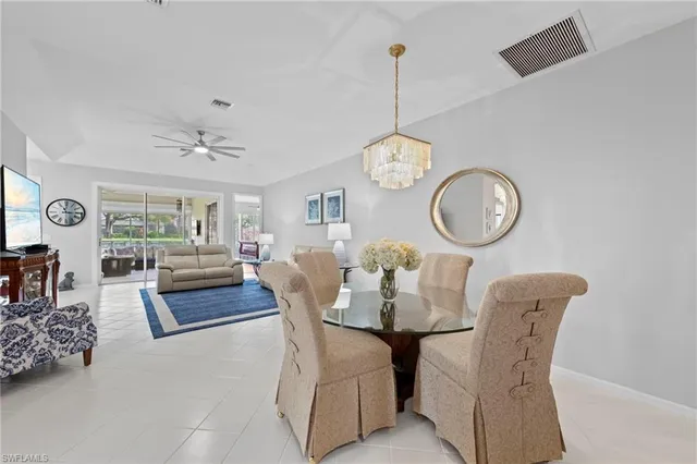 a dining room with wooden floor a chandelier a glass table and chairs