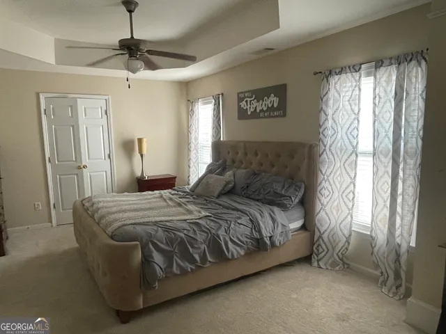 a bed sitting in a bedroom next to a window and a chandelier